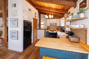 A kitchen with wooden cabinets, a black refrigerator, a stove, and a coffee maker. - Villa Delfino - 4 BR 3 Bth dog-friendly, bay home with pool and dock (Virginia Beach)