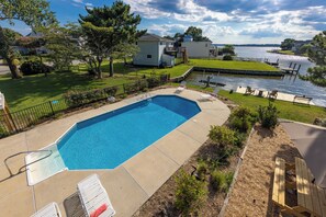 A rectangular swimming pool with a metal ladder, surrounded by a concrete deck. There are lounge chairs and a small table on the deck. - Villa Delfino - 4 BR 3 Bth dog-friendly, bay home with pool and dock (Virginia Beach)