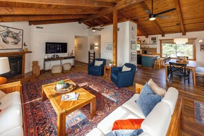 A spacious living area with a large wooden ceiling, a television mounted on the wall, and a kitchen area with a bar. - Villa Delfino - 4 BR 3 Bth dog-friendly, bay home with pool and dock (Virginia Beach)