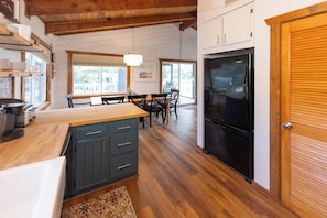 A kitchen with wooden cabinets, a black refrigerator, and a dining area with a table and chairs. - Villa Delfino - 4 BR 3 Bth dog-friendly, bay home with pool and dock (Virginia Beach)