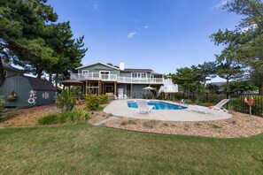 A two-story house with a backyard featuring a swimming pool, lounge chairs, and a deck. - Villa Delfino - 4 BR 3 Bth dog-friendly, bay home with pool and dock (Virginia Beach)