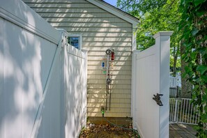 A gated backyard with a hose and various bottles on a wall-mounted rack. - Whispering Waters on Bearse Pond (Centerville)