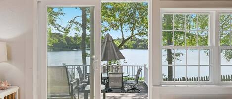 A wooden deck with outdoor furniture, a covered seating area, and a view of a lake.