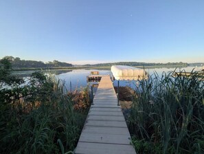 Un moll de fusta que condueix a una barca sobre un llac tranquil, sota un cel serè.