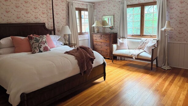 A bedroom with a bed, dresser, chair, and a window with curtains. - Charming 4-bedroom lake cabin with a dock + AC in Excelsior (Excelsior)