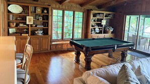 A wooden interior with a billiards table, shelves with various items, and a dining area. - Charming 4-bedroom lake cabin with a dock + AC in Excelsior (Excelsior)