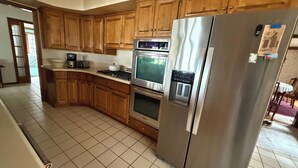 A kitchen with wooden cabinets, a stainless steel refrigerator, a built-in oven, and a coffee maker. - Charming 4-bedroom lake cabin with a dock + AC in Excelsior (Excelsior)