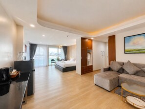 A modern hotel room with a bed, sofa, TV, and a view of the city.