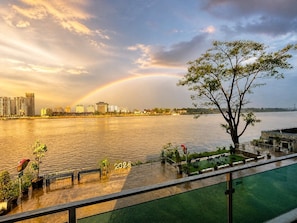 A waterfront view with a rainbow, a tree, and a building labeled '2025' in the foreground. - Dview Golden Triangle Hotel Chiangsaen (Chiang Saen)
