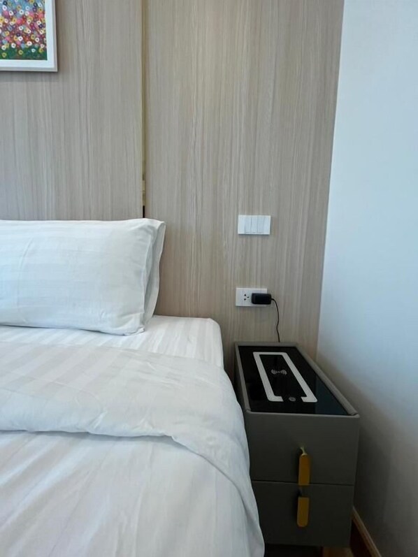 A hotel room with a bed, a bedside table with a power strip, and a wall-mounted outlet. - Dview Golden Triangle Hotel Chiangsaen (Chiang Saen)
