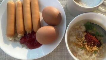 Un plato con salchichas y huevos, un tazón de sopa de verduras y una taza de té sobre una mesa.