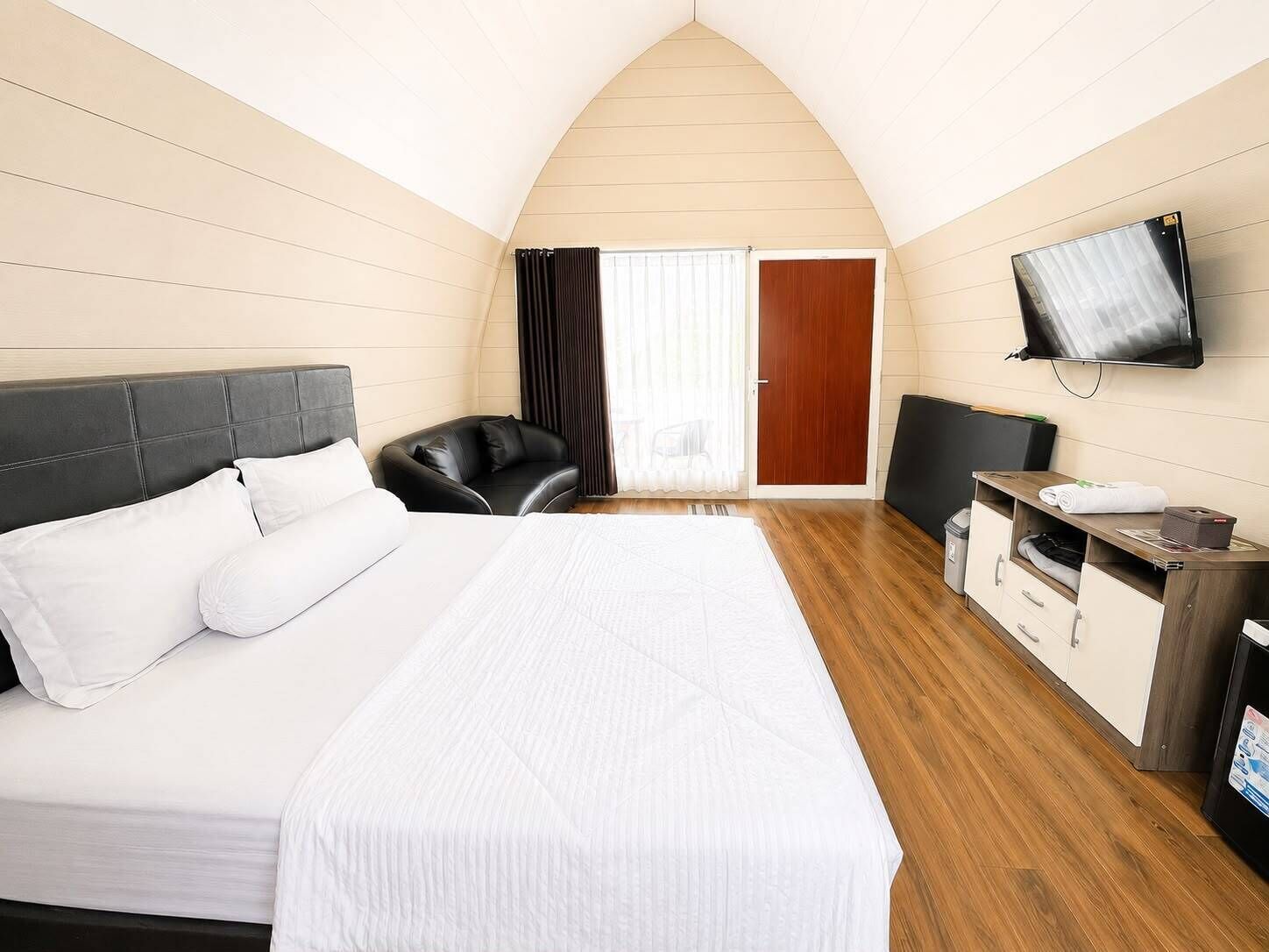 A hotel room with a bed, a desk, a chair, a television, and a sliding door.