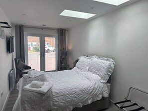 Un dormitorio moderno con una cama, una silla, una lámpara y vistas al exterior.