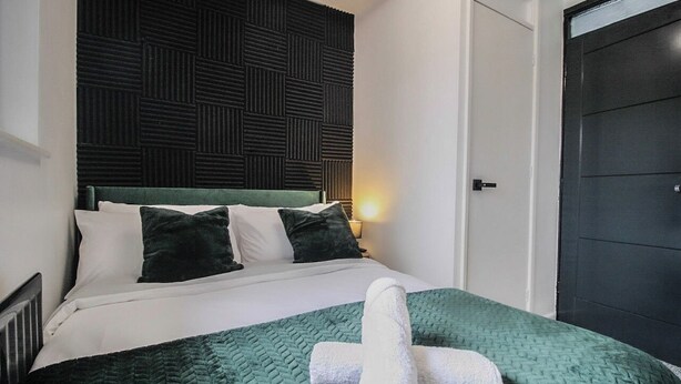 A hotel room with a bed, a dark headboard, and a door. - Hockley 4-Bed, Sleeps 13 w/ Garden & Free Parking (Birmingham)