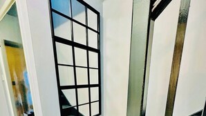 A room with a large window, a staircase, and a door leading to another area. - Hockley 4-Bed, Sleeps 13 w/ Garden & Free Parking (Birmingham)