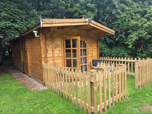 A wooden cabin with a fenced porch, a door, and a window.