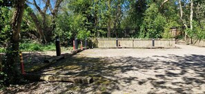 A fenced area with trees and a wooden structure in the background.