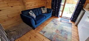 A room with a blue sofa, a patterned rug, and wooden walls. - Badger Lodge dog friendly nr Anderby Creek (Alford)