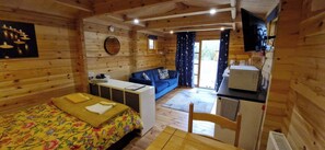 Ein Holzblockhaus-Interieur mit einem Bett, einer Couch, einem Schreibtisch und einem Fernseher.
