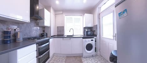 Una cocina compacta con estufa, horno, microondas y lavadora.