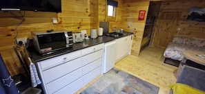 Eine kompakte Küche mit Mikrowelle, Kaffeemaschine und kleinem Kühlschrank.