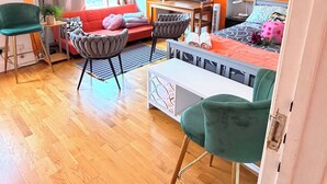 A modern living room with a sofa, chairs, a TV, and a painting on the wall. - Apartment Sleeps 8 in Fulham-Chelsea (London)
