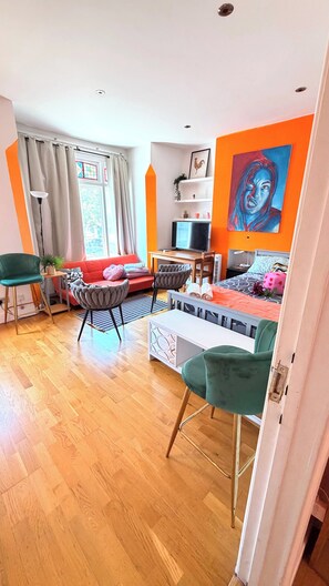 Ein modernes Wohnzimmer mit einer Couch, Sesseln, einem Fernseher und einem Bild an der Wand.