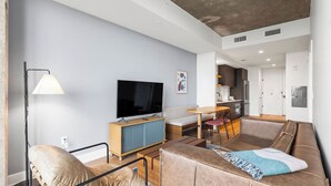 Ein modernes Wohnzimmer mit Sofa, Fernseher und Essbereich.