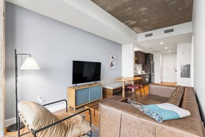 Ein modernes Wohnzimmer mit Sofa, Fernseher und Essbereich.