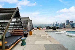 Eine Dachterrasse mit Sitzbereichen und Pool, mit Blick auf die Stadt.