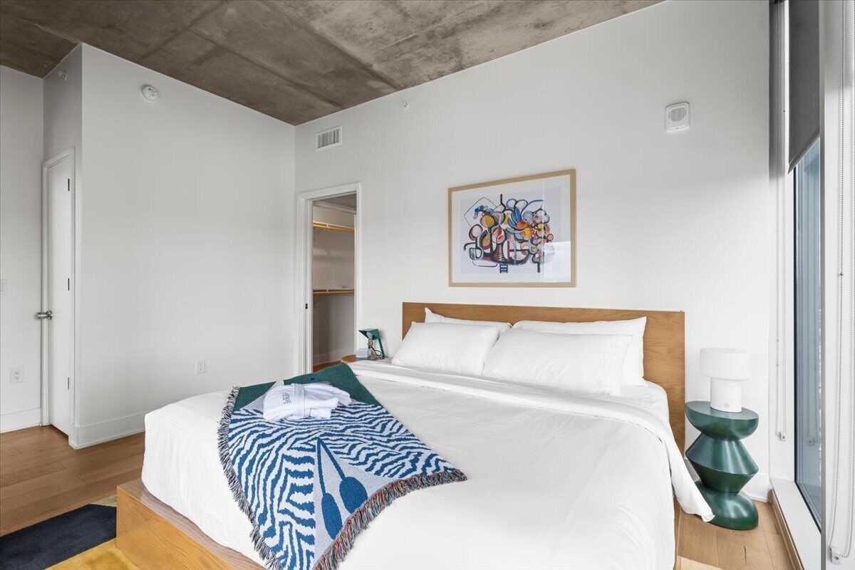 Un dormitorio con cama, un cuadro en la pared y una ventana.