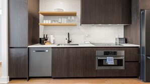 Uma cozinha moderna com armários de madeira escura, eletrodomésticos de aço inoxidável e forno embutido.
