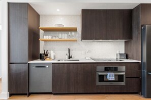 Eine moderne Küche mit dunklen Holzschränken, Edelstahlgeräten und einem eingebauten Backofen.