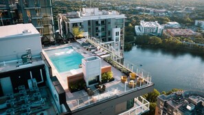 A rooftop pool with lounge chairs and a view of a river and surrounding buildings. - 2601 ATX Skyline Corner Retreat | Rooftop Pool, Skyline Views, Rainey St (Austin)