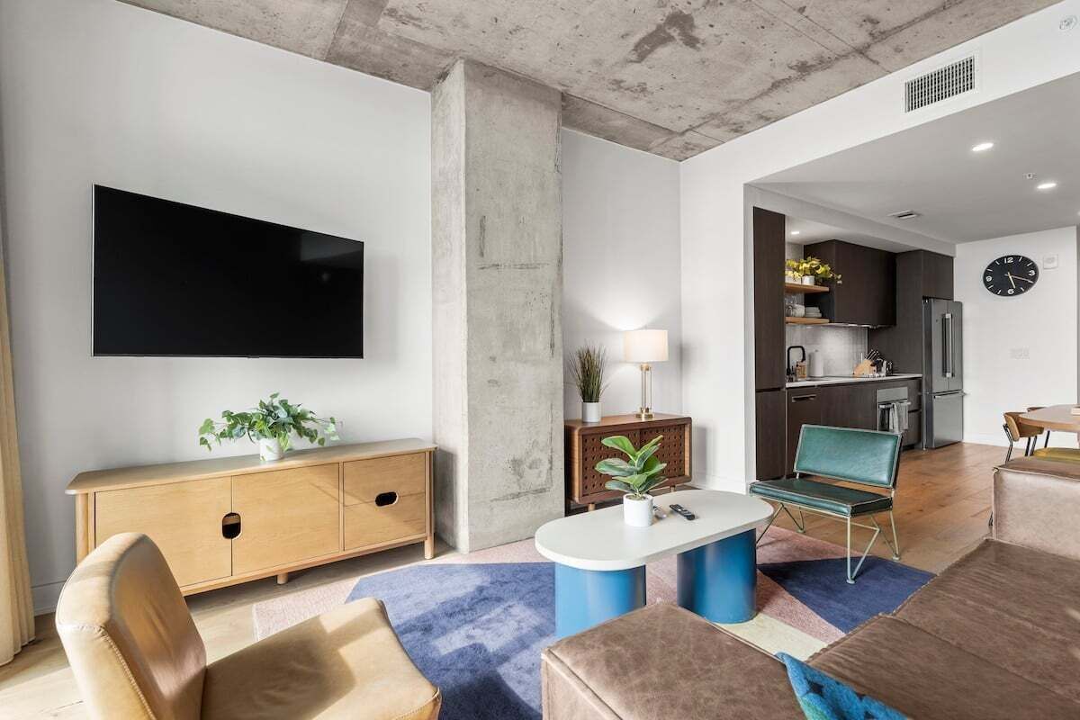 Ein modernes Wohnzimmer mit Flachbildfernseher, einer Couch, einem Couchtisch und einem Essbereich mit einem Stuhl.