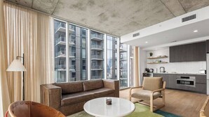 A modern living room with a sofa, a round table, and a chair. - Sunset Condo | Downtown Austin *Rooftop Pool* & City Views! (Austin)