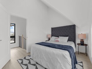 Un dormitorio con una cama grande, dos mesitas de noche, una ventana y vistas al exterior.