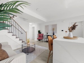 A modern living room with a staircase, a dining area, and a kitchen. - Cozy 2BR Penthouse Apt with Rooftop and Parking, Near to Falls (Niagara Falls)