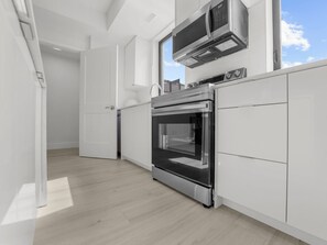 Una cocina moderna con armarios blancos, horno empotrado y microondas.