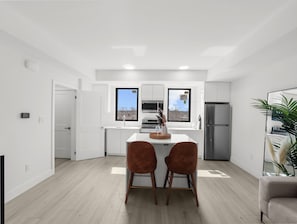 Eine moderne Küche mit weißen Schränken, einer zentralen Kochinsel und einem Edelstahl-Kühlschrank.