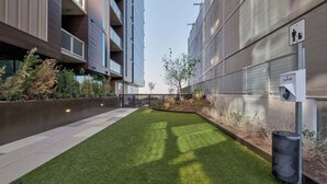 Un edificio moderno con un patio, un bote de basura y un letrero que indica el baño de hombres.
