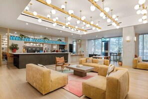 A modern interior with a central kitchen, sofas, and a dining area. - Prestige Lakeview Condo on Rainey + Rooftop Pool | Sleeps 8 (Austin)