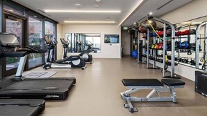 A gym with treadmills, elliptical machines, a bench press, and weightlifting equipment. - Sunny Corner DT Suite * Pool * Walk to 6th, Rainey (Austin)