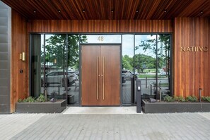 Ein moderner Gebäudeeingang mit Holzfassade, einer großen Glasdoor und einem Schild mit der Aufschrift 'NATIIVO'.