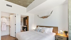 A bedroom with a large bed, bedside tables, a wardrobe, and a decorative horn on the wall. - Lux Longhorn Chic | * Downtown * W/D * Pool (Austin)