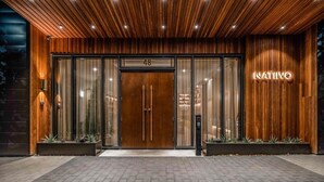 A modern hotel entrance with a wooden facade, a glass door with a number '48', and a neon sign reading 'NATIVO'. - Lux Longhorn Chic | * Downtown * W/D * Pool (Austin)