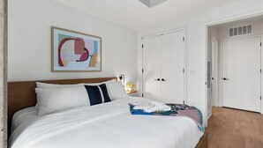 A hotel room with a bed, a nightstand, a painting, and a wardrobe. - Rainey Street Lux High Rise Condo | Rooftop Pool! (Austin)