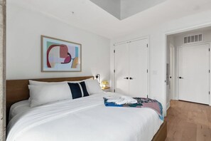 Ein Hotelzimmer mit Bett, Nachttisch, einem Bild und einem Kleiderschrank.