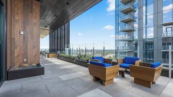 Un espacio exterior moderno con mobiliario de madera y vistas a la ciudad.