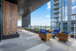 A modern outdoor seating area with wooden furniture and a view of the city.